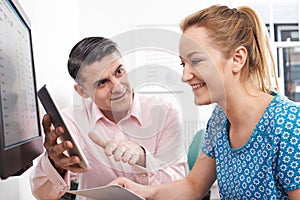 Man Training Woman In Office Using Digital Tablet