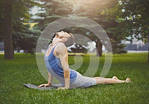 Man training yoga in cobra pose outdoors