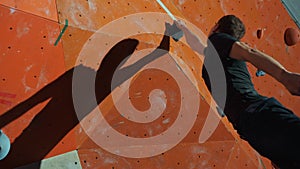 A man trains on a climbing wall, performs a difficult jump and grabs a stone