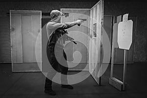 A man trains tactical shooting with a rifle and a pistol at a shooting range at a target. Black and white photo