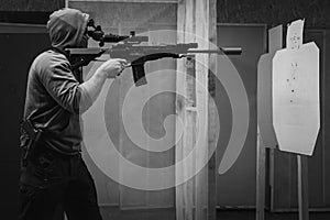 A man trains tactical shooting with a rifle and at a shooting range at a target. Black and white photo