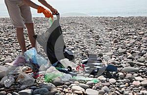 Man with trash bag collecting garbage in nature, closeup. Environmental Pollution concept