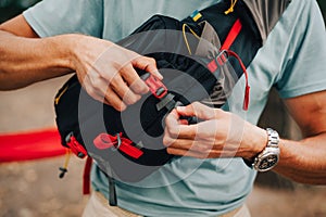 Man with a travel bag on his shoulder snaps fastex on a waist bag. Advertising, close-up photo of a waist bag for hiking on a man
