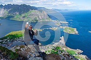 Man travel blogger taking photo by smartphone hiking in Norway, Lofoten islands Influencer lifestyle