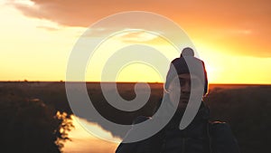 A man traveler with a backpack on his shoulders walks along a high mountain at sunset in the sky, overcome obstacles and