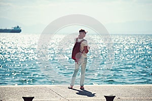 Man traveler with backpack looking far away at sea water. travel and wanderlust concept. summer vacation and adventures