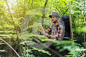 Man traveler with backpack and map searching directions in the forest