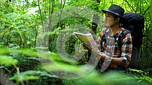 Man traveler with backpack and map searching directions in natural forest