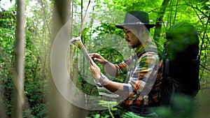 Man traveler with backpack and map searching directions in natural forest