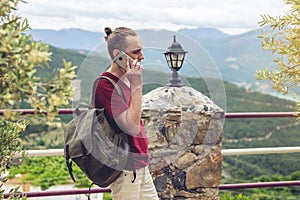 Man traveler with backpack talking on the phone on a background of mountains