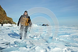 A man is a traveler behind the transparent ice floe of the frozen Lake Baikal. Winter trip