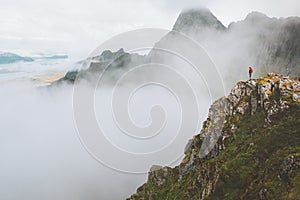 Man traveler in foggy mountains on rocky cliff edge solo travel active lifestyle