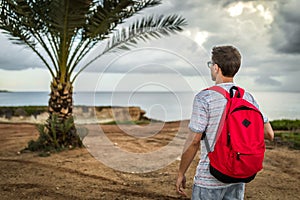 Man traveler freelancer lifestayler stands back with a red backpack
