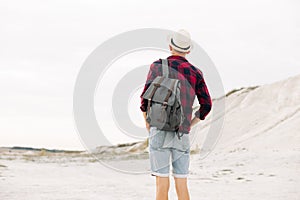 Man traveler in a hat and with a backpack walks along a mountain road, man travel hiking in the Scandinavian mountains