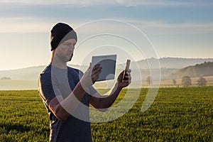 Man, traveler in hat pairing tablet and mobile phone in spring fog Czech landscape photo