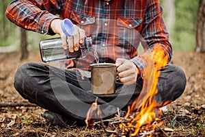 Man traveler pours water from a bottle into a metal mug. photo