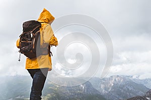 Man traveler in raincoat and backpack enjoying view of mountains
