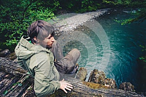 Man Traveler relaxing on wooden bridge over river