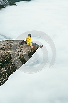 Man traveler sitting on Trolltunga rocky cliff edge