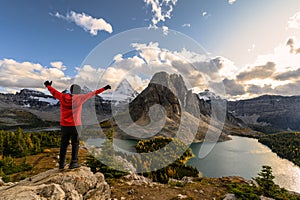 Man traveler stand with raised hands on Niblet with Mount Assiniboine in provincial park photo