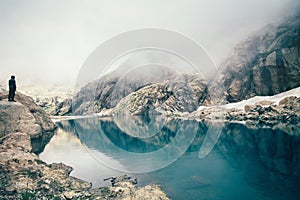 Man Traveler standing alone on cliff lake