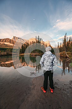 Man traveler standing enjoy the scenery of Three Sisters Mountains reflection on river in autumn at morning