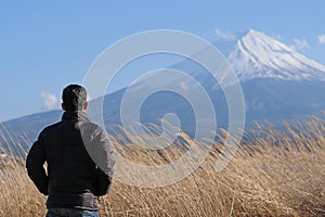 Man traveler standing and looking Beautiful Mount Fuji with snow capped and blue sky at Lake kawaguchiko, Japan