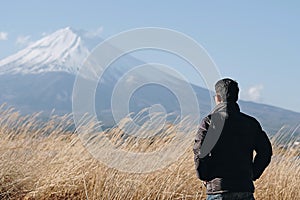 Man traveler standing and looking Beautiful Mount Fuji with snow capped and blue sky at Lake kawaguchiko, Japan