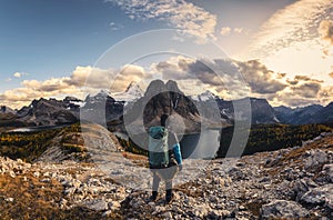 Man traveler standing on Nublet peak with rocky mountains and lake in Assiniboine provincial park