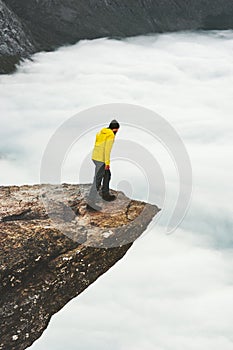 Man traveler standing on Trolltunga rocky cliff edge