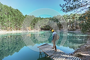 Man traveler walking alone to blue lake in woods