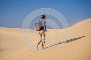 Man traveling in the desert. Sandy dunes and blue sky on sunny summer day. Travel, adventure, freedom concept. Tourism