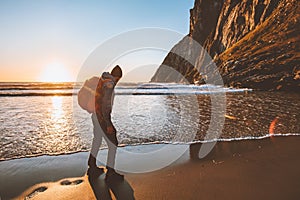 Man traveling hiking with backpack on sandy beach sunset ocean view adventure lifestyle