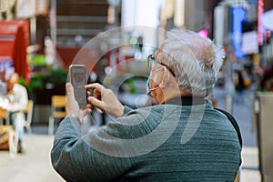 Man traveling looking at in smartphone on Times Square, Manhattan, New York City wearing a face mask in covid-19 pandemic season photo