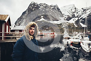 Man traveller sitting on a pier in Reine village, Norway