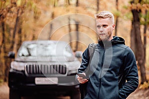 The man travels by car. The guy on the phone looks at where he is on the navigator. Hiker lost in the autumn forest concept