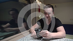 Man travels in a train carriage and talks via video conference using a smartphone while sitting at a table