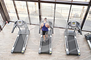 A man on a treadmill is engaged in cardio training. Workout in the gym. Body workout, leg muscles strengthening