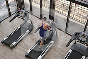 A man on a treadmill is engaged in cardio training. Workout in the gym. Body workout, leg muscles strengthening