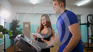 Man on a treadmill in the gym Girl on the treadmill trainer, sports a healthy lifestyle