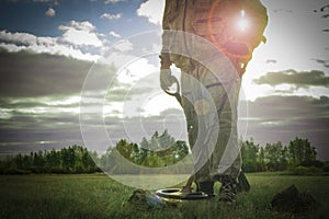 Man on a treasure hunt with a metal detector in the woods on the field