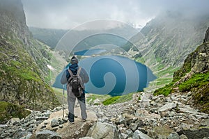 A man with trekking poles looking at lake in Tatra Mountains