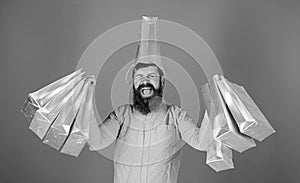 Man with trendy beard wearing pink shirt and silver bag on his head isolated on blue background. Shopping champion