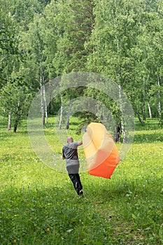 Man tries to inflate an air sofa. Motions blur. in the forest background