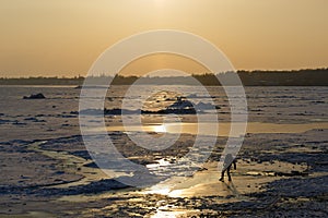 Man tries to pass on the thin ice of a frozen sea on a winter evening