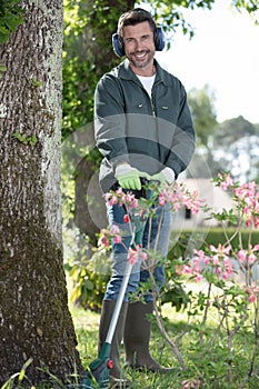man with trimer mows grass in courtyard