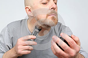 Man trimmer corrects his beard