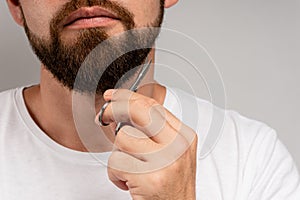 Man trimming his beard with a scissors