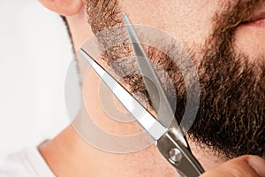 Man trimming his beard with a scissors