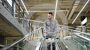 A man with a trolley on escalator in a hardware store